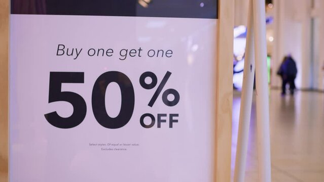 Minimalistic sign Buy one Get one Free sale promotion in modern shopping mall. Signboard stand with seasonal Black Friday discount in clothing store. Shopping concept on Black Friday with discount.