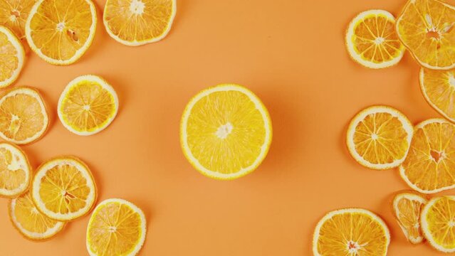 Woman hand put a cut of lemon on the table. Fresh aroma citrus slices on orange background top view, close-up. Summer bright texture studio shot for shop, supermarket, restaurant