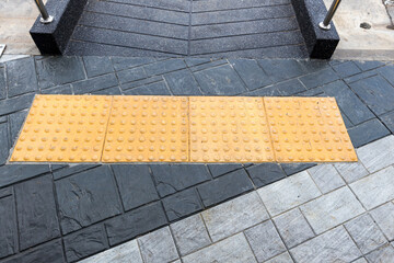Concrete ramp way with yellow braille block tiles. Concrete ramp way with stainless steel handrail...