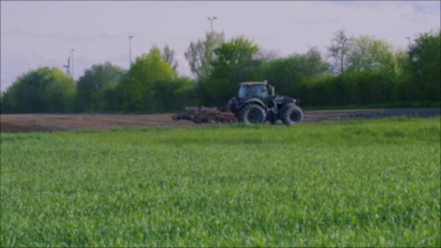 Background, blurry image. On the field, the tractor plows the ground. Side view. Agricultural concept.