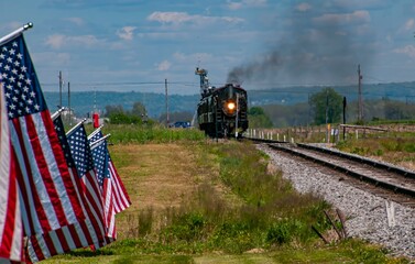 A View of an Antique Steam Engine Approaching, Blowing Smoke and a Row of American Flags Blowing...