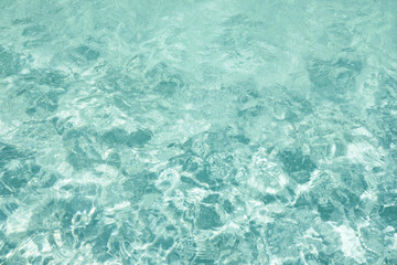 Abstract water background with ripples. Light caustics effect. Play of light and shadow, texture of twaves and splashes.