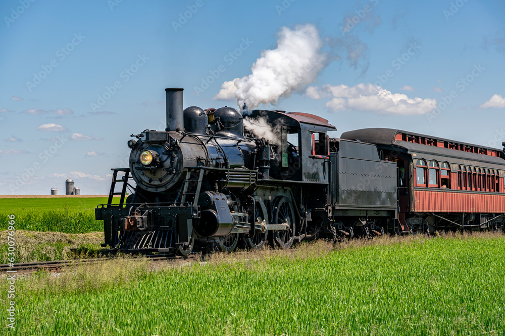 Wall mural A View of An Approaching Antique Restored Steam Passenger Train,, Blowing Smoke and Traveling Thru Farmlands on a Sunny Spring Day - Wall murals