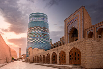 Old city view with iconic Kalta Minor minaret and ancient madrasah at sunset, Khiva, Uzbekistan