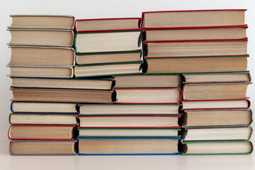Stacks of thick old books in different bindings colors sizes lying and standing on light background
