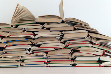 Stack of widely opened thick old books in different bindings lying one on top of other in mess