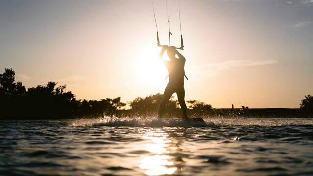 Kitesurfer silhouette on the water against bright evening sun in Egypt.