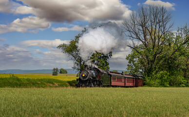 A View of an Antique Steam Passenger Train Approaching, Traveling Thru Rural Countryside, Blowing...