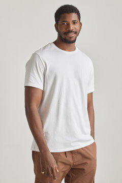 Minimal portrait of handsome black man posing in studio against white background wearing white shirt