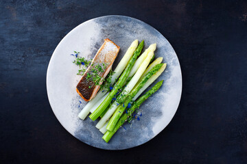 Traditionell gedämpfter grüner und weißer Spargel mit Lachs Filet und Kräuter serviert als Draufsicht auf einem Design Teller mit Textfreiraum 