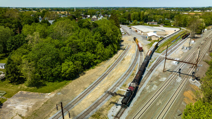 Fototapeta na wymiar An Aerial View of a Steam Locomotive Moving Freight Cars Around in a Freight Yard to Organize a Freight Train on a Sunny Day
