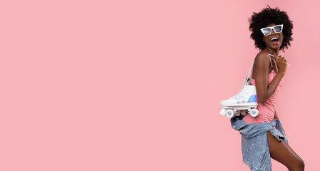 Happy black woman with roller skates on pastel pink background.