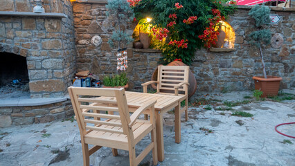 Fototapeta na wymiar Aegean, Mediterranean type garden consisting of a large garden fireplace, wooden table armchair, pottery jugs and plants in pots