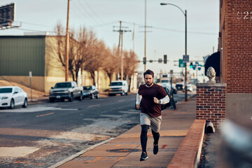 Young man jogging in a town on a street