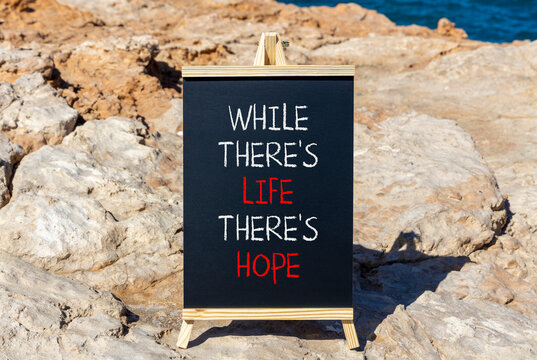 Life and hope symbol. Concept word While there is life there is hope on beautiful black chalkboard. Beautiful stone sea background. Business lifestyle life and hope concept. Copy space.