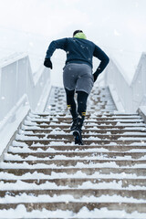 Handsome middle age man with a beard running and exercising outside on extremely cold and snowy...