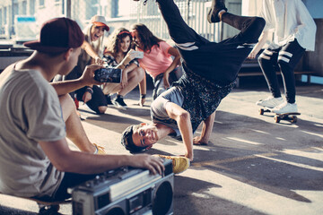 Group of young people break dancing in a parking lot and recording with their smart phone © Geber86