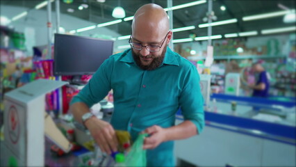 Naklejka na ściany i meble Joyful Brazilian Supermarket Employee at Checkout Scanning and Bagging Products, Smiling at Camera in South American Grocery Market Scene