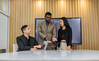 Three diversity of businesspeople wearing formal clothes, meeting, discussing and brainstorming their ideas for planning project, using laptop, sitting in modern indoor office or working space.