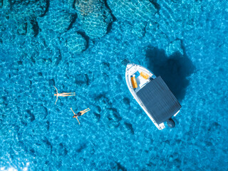 Aerial view of alone small motorboat and swimming people in the sea in summer sunny day. Beautiful...