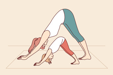 Mother and daughter are engaged in yoga and exercises, leading healthy lifestyle and learning good habits that improve well-being. Woman with little girl doing yoga pose adho mukha svanasana together