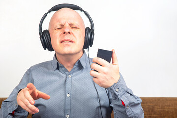 man with closed eyes listens to music with headphones on a light background