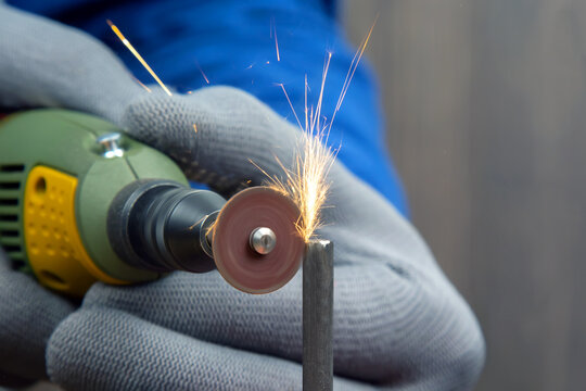 Worker processes metal with engraving drill close-up. The work of the dremel engraving electric tool. Industrial metal processing
