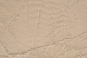 Transparent sea water over the yellow sand of the coast.