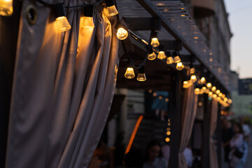 Lights of a beautiful light garland of a cafe patio on a city street.