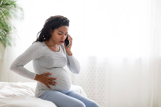 Pregnant African American Woman Feeling Pain In Belly, Calling Doctor On Cellphone