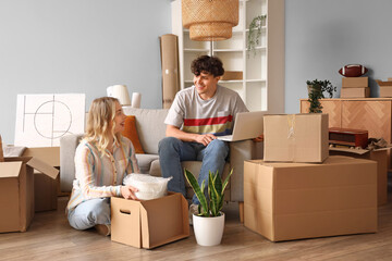 Young couple using laptop in room on moving day