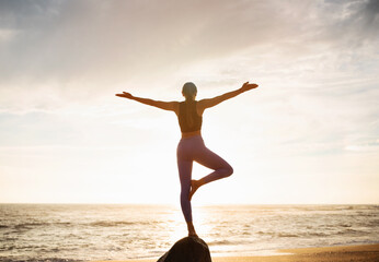 Fototapeta premium Young slim caucasian lady in sportswear practice yoga on stone, enjoy breathing exercises, balance and freedom