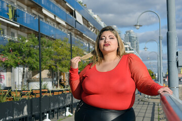 portrait of beautiful plus size latin woman in red clothes standing outdoors posing, copy space