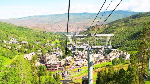Beaver Creek ski resort with riding ski lift gondola cable car in summer at Vail Resorts village buildings town with mountains pov point of view shot