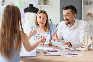 Fototapeta premium Young couple with pictures planning their wedding in office