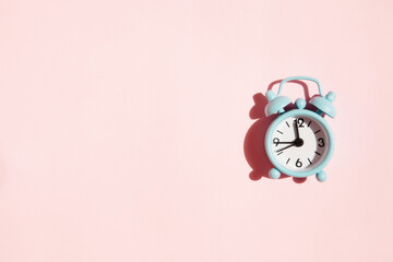 Blue alarm clock on pink background with copy space, time flies or deadline concept