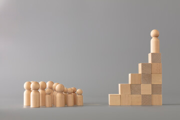 Leader figure standing out from crowd on wooden cubes, other figures in front on floor. Leadership and team. Boss and subordinates. Individual and superiority concept on grey background. - Powered by Adobe