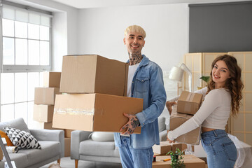 Young couple with cardboard boxes in room on moving day