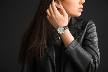 Stylish beautiful woman with wristwatch on black background
