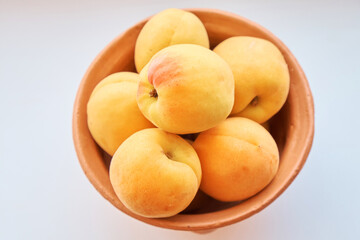 Apricots lie in a clay jug on a white background. View from above. Up close