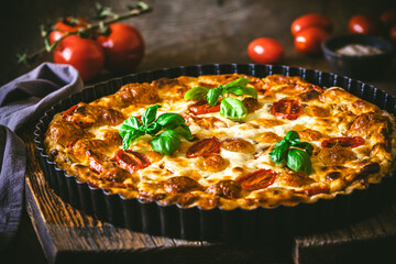 Whole tomato quiche with basil on wooden background