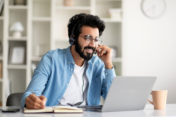 Online Education. Indian Smiling Man In Headset Study With Laptop At Home - obrazy, fototapety, plakaty