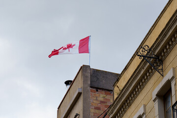 The Canadian flag flutters in the wind on a building