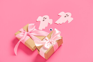 Composition with beautiful gift boxes and ghosts made of paper for Halloween on pink background, closeup