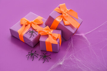 Composition with spiders and gift boxes for Halloween on purple background