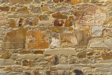The texture of the old medieval wall of the house, lined with brown stone