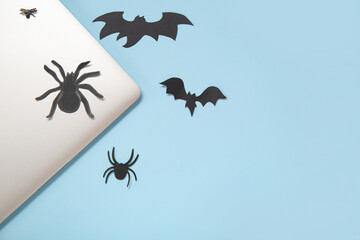 Modern laptop and paper decor for Halloween on blue background, closeup