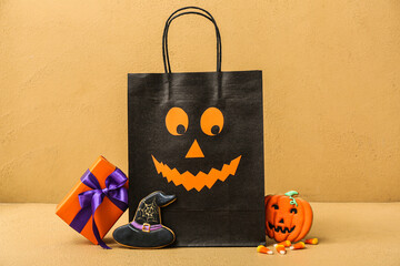 Composition with shopping bag, gift box and tasty cookies for Halloween on beige background