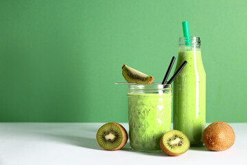 Glass and bottle of fresh kiwi smoothie on white table