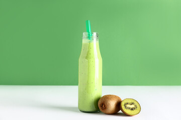 Bottle of fresh kiwi smoothie on white table
